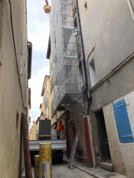 Chantier de rénovation de toiture complexe : montage des échafaudages, évacuation des gravats dans une rue étroite du centre ville de la Ciotat, près de Cassis